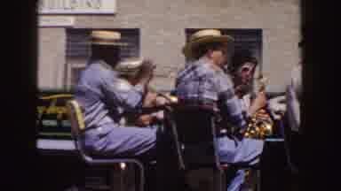 South Dakota (1954): Three People Eating Picnic Meal In Shade While Brass Band