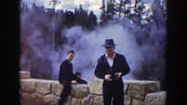 Wyoming (1939): People Standing Near Tan Stone Barrier Of Geyser On A Clear Day