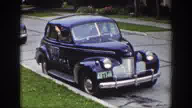 Wyoming (1939): Person Waves From Departing Dark Blue Car On A Clear Day