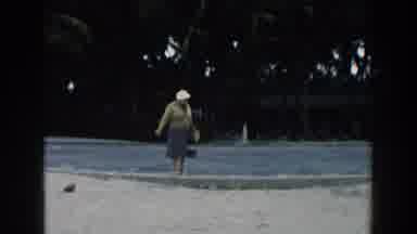 Miami Florida (1960): Woman Wearing Blue Dress And White Hat Waves To Camera On A