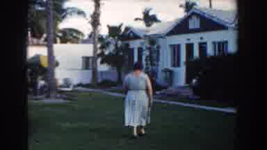 Miami Florida (1960): Woman In Blue Dress Walking Across A Lawn To A Bungalow