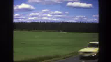 Sweden (1975): Driving Down A Road On A Sunny Day Beside A Grassy Field