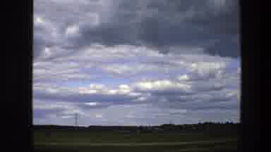 Sweden (1975): Passing View Of Green Fields Blue Sky And Gray Clouds On A Clear