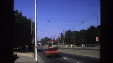 Sweden (1975): A Trolley Car Passing Through A City With Some Cars At An Avenue