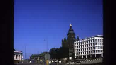 Sweden (1975): A Bird Flying By A City Landscape With Cars And People Walking By