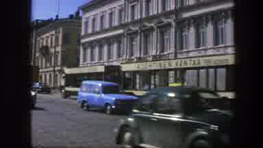 Sweden (1975): A Streetcar And Several Cars Driving Down A City Street With