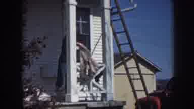 Nebraska (1958): A Woman Standing On The Porch Of A House And Shaking Out A