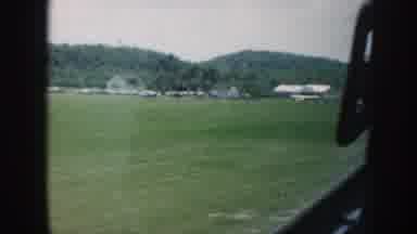 Nebraska (1958): Passing View Of Green Grass Trees And White Building On A Clear