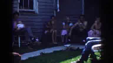 Nebraska (1958): Several People Sitting Around In A Yard With A House In The