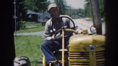 Nebraska (1958): A Man Driving A Yellow Tractor And People Standing On A Porch