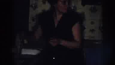 Nebraska (1958): Woman Wearing Brown Dress Washes Gray Item In Sink While Man