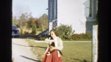 Michigan (1958): Young Girl Standing On Sidewalk In Front Of House Holding A