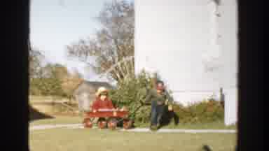 Michigan (1958): Boy Wearing Green Jacket Pulls Girl Wearing Red Coat In Red Wagon