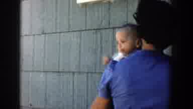 Michigan (1958): Caucasian Woman Holding Baby Over Shoulder Walking Away Outside