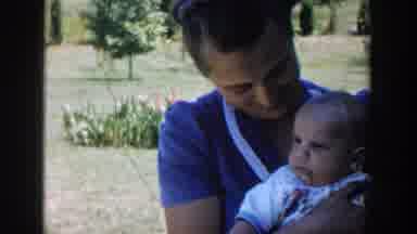 Michigan (1958): A Veiled Woman Holding Her Baby As She Watches His Siblings Play