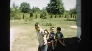 Michigan (1958): Boy Wearing Gray Pants Pulls Two Kids Sitting In Red Wagon On A