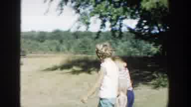 Michigan (1958): Two Kids Wearing Brown Print Shirts Eat Blue Candy On A Clear Day
