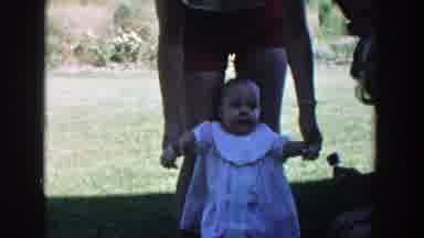 Michigan (1958): A Woman In Red Shorts Holds An Infant's Arms To Help It Stand Up