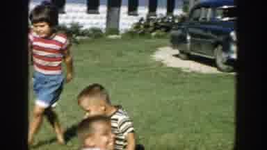 Michigan (1958): Children Play In A Backyard In Front Of A White House And A Blue