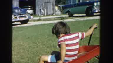 Michigan (1958): Children Playing With Carts On A Green Field Of A House In The