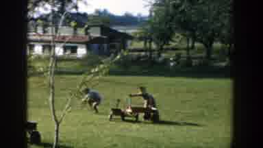 Michigan (1958): Three Kids Playing With Wagons On Green Grass On A Sunny Day