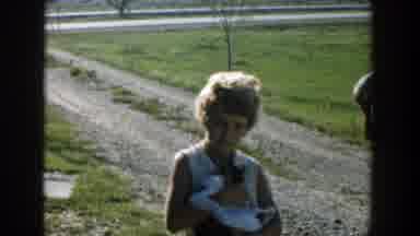 Michigan (1958): An Elderly Woman Holds A Cat While Watching Three Boys Ride On