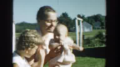 Michigan (1958): Woman Wearing White Shirt And Glasses Holds Baby Wearing White