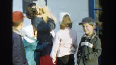 Michigan (1958): Woman Wearing Gray Coat Holds Toddler Wearing Yellow Coat On A