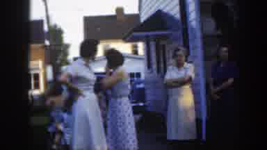 Massachusetts (1949): A Group Of Adults Stand Outside A House In A Neighborhood