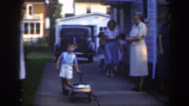 Massachusetts (1949): Boy Wearing White Shorts Pushes Yellow Wagon On A Clear Day