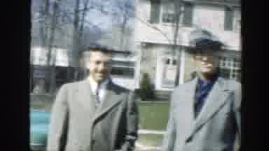 Massachusetts (1949): Two Men Wearing Gray Coats Stand Near A White House On A