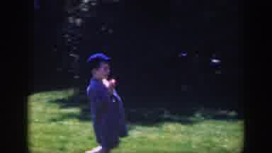 Massachusetts (1949): Boy Wearing Blue Hat Holds Red Object While Walking On Green