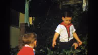 Glendale California (1962): Toddler Wearing Red Romper Watches Small Boy Wearing
