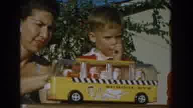 Glendale California (1962): Woman Wearing White Earrings Sets Yellow Toy Bus In