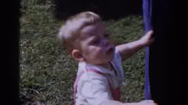 Glendale California (1962): Young Girl Wearing Pink Overalls Hugging The Legs Of
