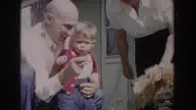 Glendale California (1962): A Child Held By An Old Man Plays With A Large Dog And