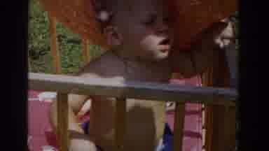 Glendale California (1962): A Baby With A Large Hat On Sits In A Crib Outside In