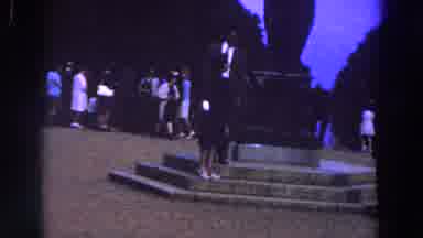 Ireland (1961): A Woman In Black Suit Standing In Front Of A Statue While People