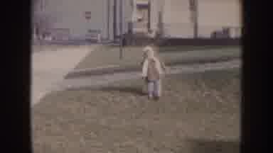 Nebraska (1957): A Little Girl Walking On A Grass Area With A City Background And