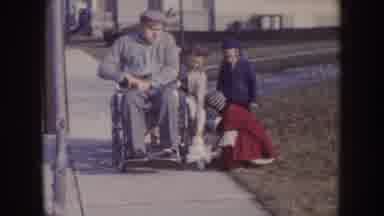 Nebraska (1957): Man In Wheelchair Is Pushed Whilst Child Plays With Toy Next To