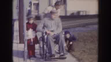 Nebraska (1957): A Woman With Two Children Walking An Elder On A Wheelchair