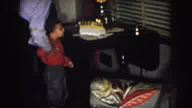 Nebraska (1957): Adult Helps Child In Red Shirt While It Blows Birthday Candles