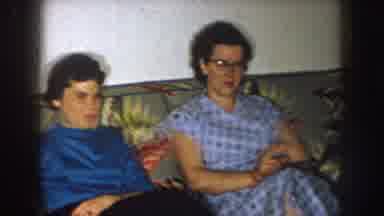 Nebraska (1957): Two Women Sit On Yellow And Gray Sofa Smoking Cigarettes