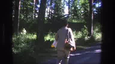 Denmark (1975): Person Wearing Tan Pants And Shirt Walks Down Dirt Road On A Sunny