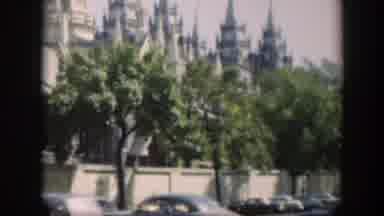 Wyoming (1951): View Of Blue Car Driving Past Tan Building And Green Tree On A