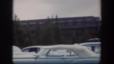 Wyoming (1951): View Of Parked Cars And Brown Building Behind Green Trees On A