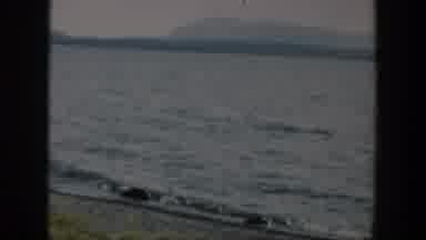 Wyoming (1951): Gentle Waves Hitting Several Small Rocks On A Bank With Sand And