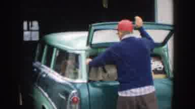 Michigan (1957): Man Closes Trunk Of Packed Green Car And Carries Child Out Of