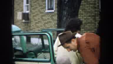 Michigan (1957): A Man Removes Items From A Car While Two Women Talk Next To The