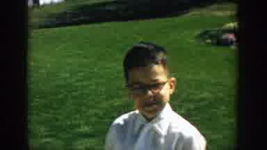 Michigan (1957): Kid With Glasses Walking Past A Car And Tries To Lift A Barrel